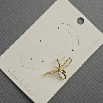 Boucle d'oreille clip «Nœud» doré en métal 17×30 mm ± strass blancs